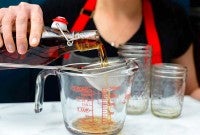 Straining homemade vanilla into a measuring cup.